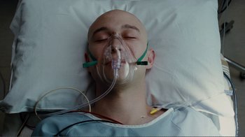 Movie still from “50/50” (2011), directed by Jonathan Levine – A man is laying in a hospital bed with a mask on his face; Close Up shot, Overhead angle