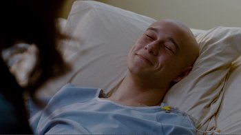 Movie still from “50/50” (2011), directed by Jonathan Levine – A bald man laying in a hospital bed smiling; Close Up shot, Overhead angle