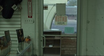 Movie still from “600 Miles” (2015), directed by Gabriel Ripstein – A view through a glass door of a building; Wide shot, Low angle