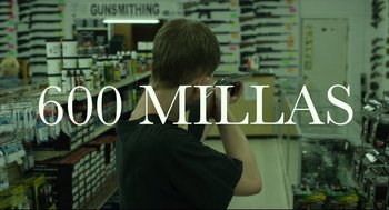 Movie still from “600 Miles” (2015), directed by Gabriel Ripstein – A young man is taking a picture in a gun store; Extreme Close Up shot, Over the shoulder angle