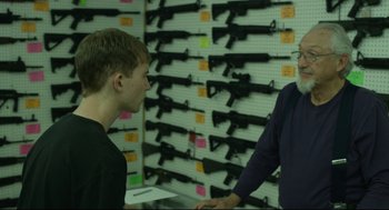 Movie still from “600 Miles” (2015), directed by Gabriel Ripstein – Two men standing in front of a wall of guns in a gun shop; Medium shot, Over the shoulder angle