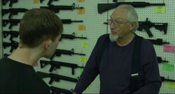 Movie still from “600 Miles” (2015), directed by Gabriel Ripstein – An older man and a young man in a gun store; Medium shot, Over the shoulder angle
