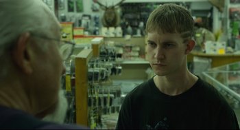 Movie still from “600 Miles” (2015), directed by Gabriel Ripstein – A young man is looking at another man in a store; Close Up shot, Over the shoulder angle