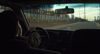 Movie still from “600 Miles” (2015), directed by Gabriel Ripstein – A person is sitting in the drivers seat of a car; Medium shot, Over the shoulder angle