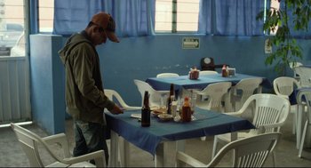 Movie still from “600 Miles” (2015), directed by Gabriel Ripstein – A man standing in front of a table with food on top of it; Medium shot, High angle