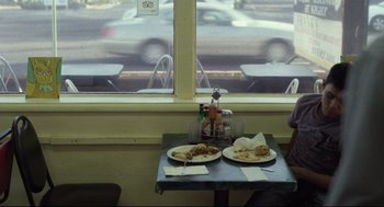 Movie still from “600 Miles” (2015), directed by Gabriel Ripstein – Two plates of food on a table in front of a window; Wide shot, High angle