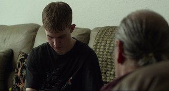 Movie still from “600 Miles” (2015), directed by Gabriel Ripstein – A young man and an older man sitting on a couch; Close Up shot, Over the shoulder angle