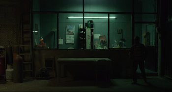 Movie still from “600 Miles” (2015), directed by Gabriel Ripstein – A dark room with a table and a chair; Wide shot, Low angle