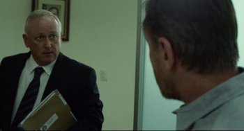 Movie still from “600 Miles” (2015), directed by Gabriel Ripstein – A man in a suit is looking at himself in the mirror; Medium shot, Over the shoulder angle