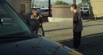 Movie still from “600 Miles” (2015), directed by Gabriel Ripstein – A man taking a picture of another man standing in front of a car; Wide shot, Over the shoulder angle