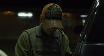 Movie still from “600 Miles” (2015), directed by Gabriel Ripstein – A man wearing a baseball cap and a green jacket; Close Up shot, Low angle