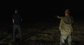 Movie still from “600 Miles” (2015), directed by Gabriel Ripstein – Two men standing in a field at night holding guns; Wide shot, Over the shoulder angle