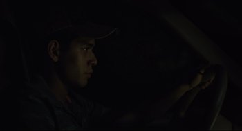 Movie still from “600 Miles” (2015), directed by Gabriel Ripstein – A man in a baseball cap sitting in a car at night; Close Up shot, Over the shoulder angle