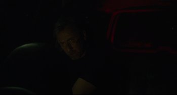 Movie still from “600 Miles” (2015), directed by Gabriel Ripstein – A man sitting in a dark room looking at the camera; Close Up shot, Over the shoulder angle