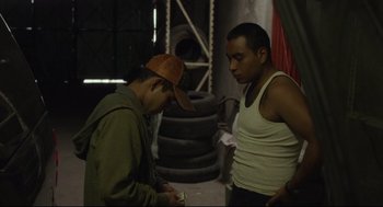Movie still from “600 Miles” (2015), directed by Gabriel Ripstein – Two men standing next to each other in a warehouse; Medium shot, Low angle