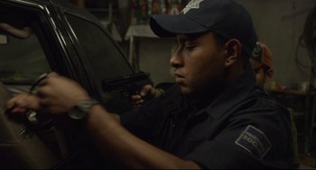 Movie still from “600 Miles” (2015), directed by Gabriel Ripstein – A police officer is holding a gun in his hand; Medium shot, Low angle
