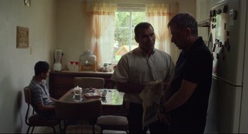Movie still from “600 Miles” (2015), directed by Gabriel Ripstein – Two men are talking in a kitchen; Medium shot, Over the shoulder angle