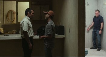 Movie still from “600 Miles” (2015), directed by Gabriel Ripstein – Two men standing in a room talking to each other; Medium shot, Low angle