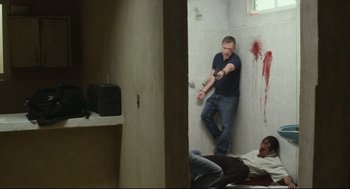 Movie still from “600 Miles” (2015), directed by Gabriel Ripstein – A man holding a knife in a corner of a bathroom; Wide shot, High angle