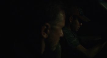 Movie still from “600 Miles” (2015), directed by Gabriel Ripstein – Two men sitting in a dark room , one of whom is wearing a baseball cap; Close Up shot, Over the shoulder angle