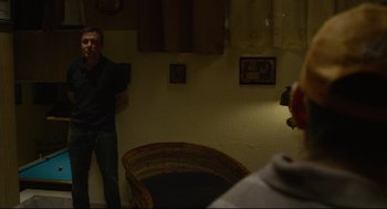 Movie still from “600 Miles” (2015), directed by Gabriel Ripstein – A man standing next to a chair in a room; Medium shot, Over the shoulder angle