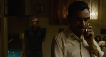 Movie still from “600 Miles” (2015), directed by Gabriel Ripstein – Two men standing in a darkened living room; Medium shot, Over the shoulder angle
