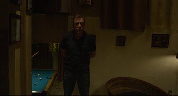 Movie still from “600 Miles” (2015), directed by Gabriel Ripstein – A man standing in front of a pool table in a room; Medium shot, Low angle