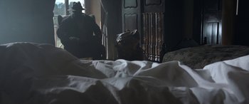 Movie still from “The Soul Collector” (2019), directed by Harold Holscher – A bag sitting on top of an unmade bed in a bedroom; Wide shot, Low angle