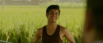 Movie still from “Dangal” (2016), directed by Nitesh Tiwari – A young man standing in front of a green field; Medium shot, Low angle