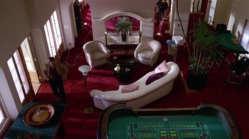 Movie still from “8 Million Ways to Die” (1986), directed by Hal Ashby – A living room filled with furniture next to a table; Extreme Wide shot, High angle