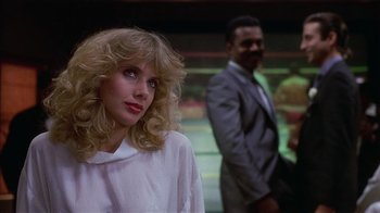 Movie still from “8 Million Ways to Die” (1986), directed by Hal Ashby – A woman standing next to a man wearing a suit; Close Up shot, Over the shoulder angle