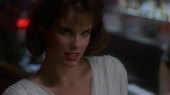 Movie still from “8 Million Ways to Die” (1986), directed by Hal Ashby – A beautiful woman in a white shirt posing for a picture; Close Up shot, Over the shoulder angle