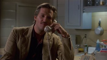 Movie still from “8 Million Ways to Die” (1986), directed by Hal Ashby – A man talking on a phone while sitting at a table; Close Up shot, Low angle