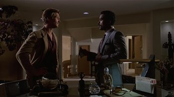 Movie still from “8 Million Ways to Die” (1986), directed by Hal Ashby – Two men standing in front of a table; Medium shot, Over the shoulder angle