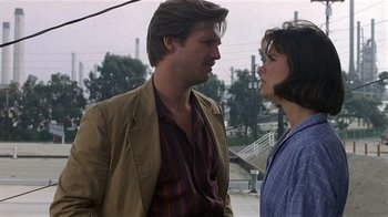 Movie still from “8 Million Ways to Die” (1986), directed by Hal Ashby – A man and a woman standing next to each other on a street; Close Up shot, Over the shoulder angle
