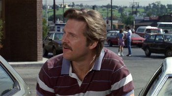 Movie still from “8 Million Ways to Die” (1986), directed by Hal Ashby – A person sitting on the ground; Close Up shot, Over the shoulder angle