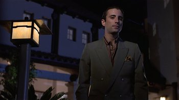 Movie still from “8 Million Ways to Die” (1986), directed by Hal Ashby – A man in a suit and tie standing in front of a building; Medium shot, Low angle