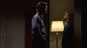 Movie still from “8 Million Ways to Die” (1986), directed by Hal Ashby – A man and a woman standing next to each other in front of a lamp; Medium shot, Low angle