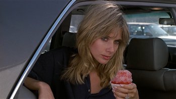 Movie still from “8 Million Ways to Die” (1986), directed by Hal Ashby – A woman sitting in the back of a car holding a shaved ice; Close Up shot, Over the shoulder angle