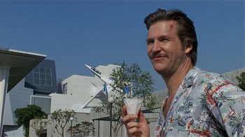 Movie still from “8 Million Ways to Die” (1986), directed by Hal Ashby – A man holding a drink in his hand and smiling for the camera; Close Up shot, Low angle