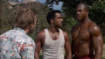 Movie still from “8 Million Ways to Die” (1986), directed by Hal Ashby – A group of men standing next to each other in a park; Medium shot, Low angle