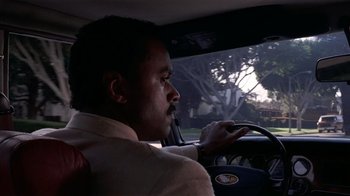 Movie still from “8 Million Ways to Die” (1986), directed by Hal Ashby – A man sitting in the driver's seat of a car; Close Up shot, Low angle