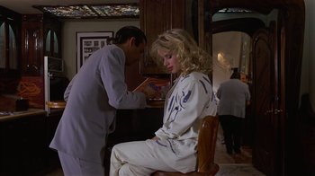 Movie still from “8 Million Ways to Die” (1986), directed by Hal Ashby – A woman sitting on a chair in front of a man; Medium shot, Over the shoulder angle