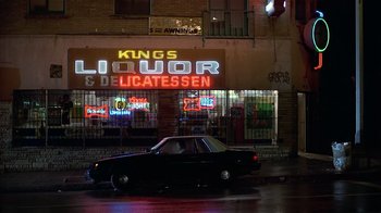 Movie still from “8 Million Ways to Die” (1986), directed by Hal Ashby – A black car parked in front of a liquor store; Extreme Wide shot, Low angle