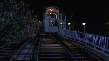 Movie still from “8 Million Ways to Die” (1986), directed by Hal Ashby – A train is going down the tracks at night time; Extreme Wide shot, High angle