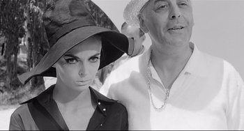 Movie still from “8½” (1963), directed by Federico Fellini – An older man and a younger woman wearing hats; Close Up shot, Low angle