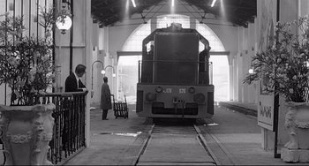 Movie still from “8½” (1963), directed by Federico Fellini – A black - and - white photo of a train in a train station; Wide shot, Low angle
