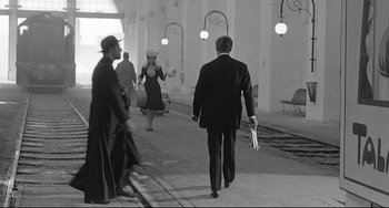 Movie still from “8½” (1963), directed by Federico Fellini – A black and white photo of a man and a woman walking; Wide shot, Low angle