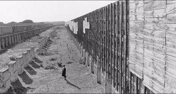Movie still from “8½” (1963), directed by Federico Fellini – A person standing in front of a wall; Extreme Wide shot, Low angle
