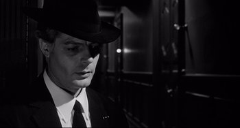 Movie still from “8½” (1963), directed by Federico Fellini – A man in a suit and a hat is looking down; Close Up shot, Low angle